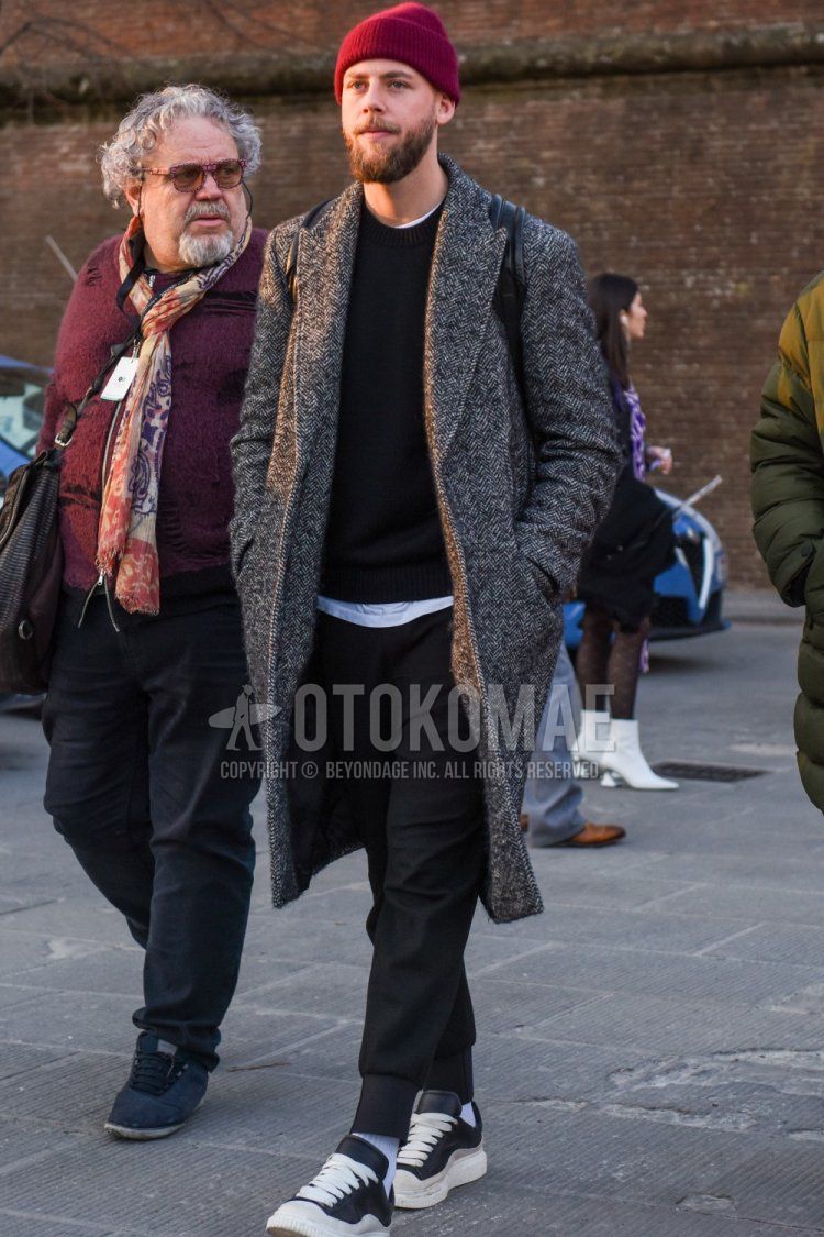Men's fall/winter outfit with red solid knit cap, gray herringbone chester coat, solid black sweater, dark gray solid jogger pants/ribbed pants, solid white socks, and black low-cut sneakers.