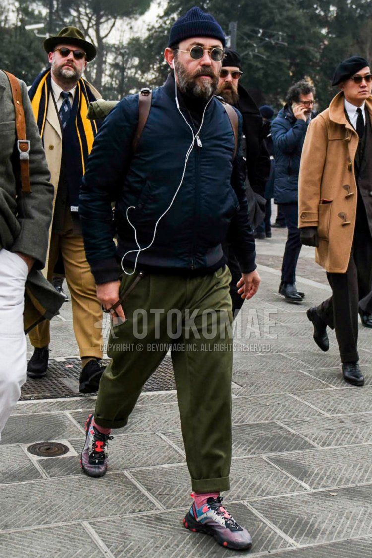 Winter men's coordinate and outfit with solid navy knit cap, solid sunglasses, solid navy MA-1, solid black turtleneck knit, solid olive green cotton pants, solid red socks, and Nike multi-colored low-cut sneakers.