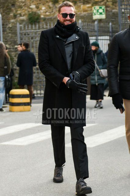 Men's fall/winter outfit with solid black sunglasses, solid black scarf/stall, solid black chester coat, solid black rider's jacket, dark gray solid slacks, and gray low-cut sneakers.