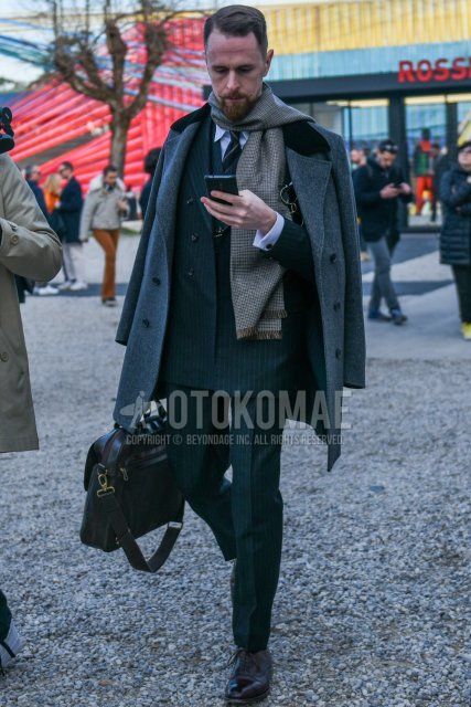 Men's fall/winter outfit with beige check scarf/stall, plain gray chester coat, plain white shirt, brown straight tip leather shoes, plain black briefcase/handbag, gray striped suit, gray regimental tie.