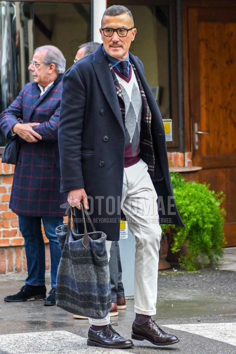 Plain glasses, plain navy chester coat, multi-colored checked tailored jacket, purple checked sweater, plain blue denim/chambray shirt, plain white cotton pants, plain brown socks, brown brogue shoes leather shoes, gray striped Winter men's coordinate/outfit with tote bag.
