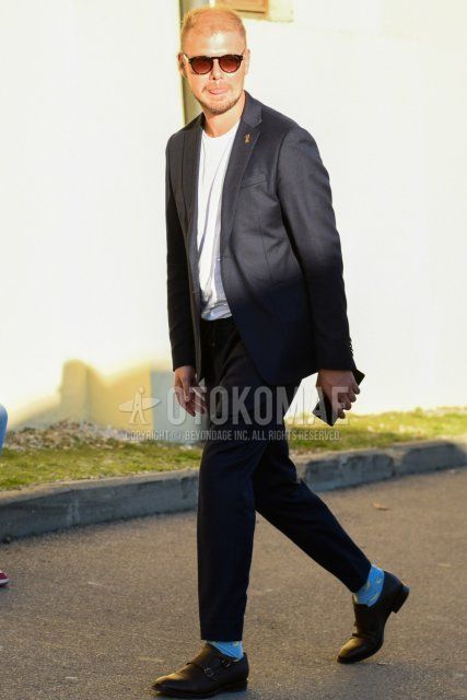 Men's spring and fall coordinate and outfit with brown tortoiseshell sunglasses, plain white t-shirt, light blue socks, black monk shoes leather shoes, and plain gray suit.