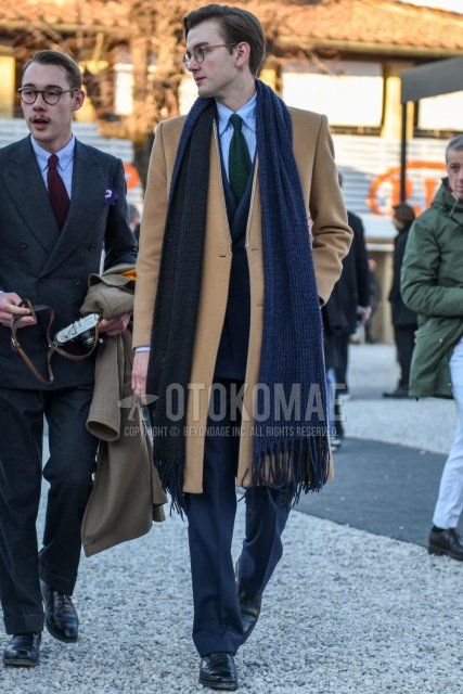 Men's fall/winter coordinate and outfit with brown tortoiseshell glasses, solid gray scarf/stall, solid beige chester coat, light blue striped shirt, black straight tip leather shoes, solid gray suit, solid green tie.