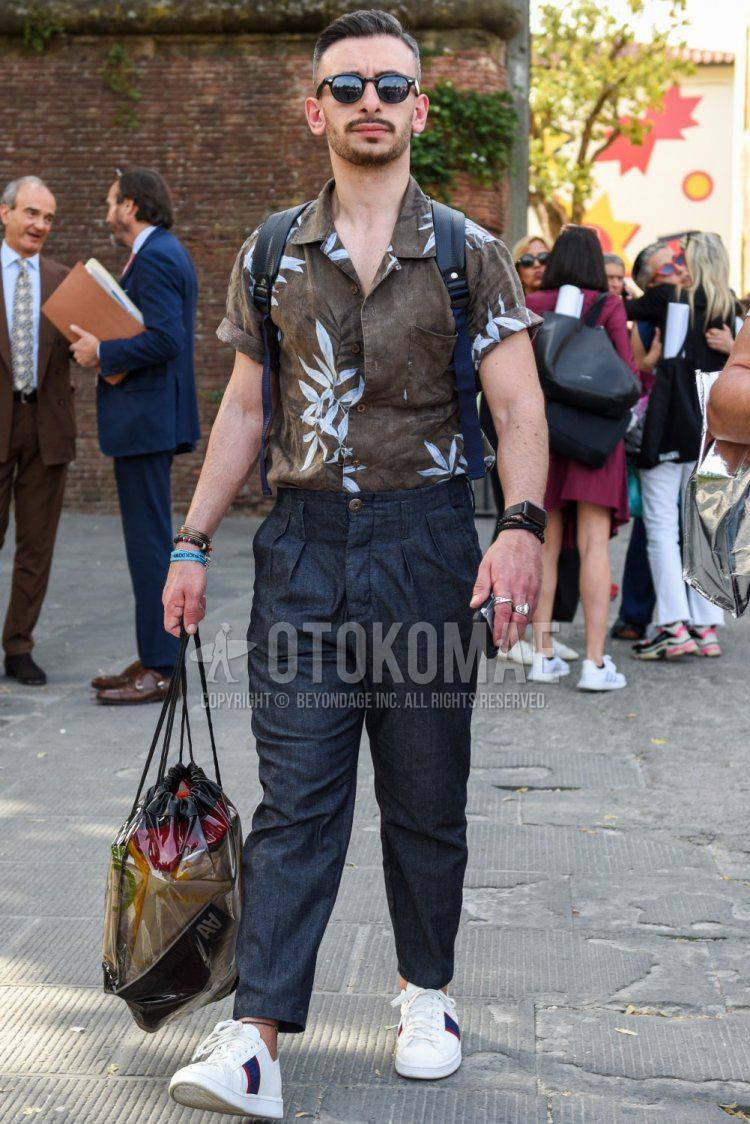Men's summer coordinate and outfit with Boston plain black sunglasses, open collar brown botanical shirt, dark gray plain ankle pants, and white low-cut sneakers.