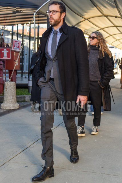 Men's fall/winter coordinate and outfit with plain black glasses, plain black trench coat, gray striped shirt, black boots, plain gray suit, and plain gray knit tie.