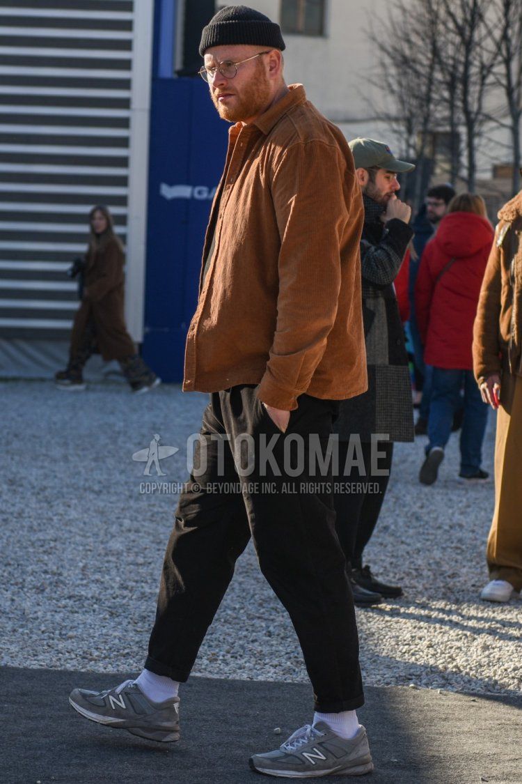 Men's spring and fall coordinate and outfit with plain black knit cap, plain silver glasses, plain brown shirt, plain black cotton pants, plain white socks, and New Balance gray low-cut sneakers.