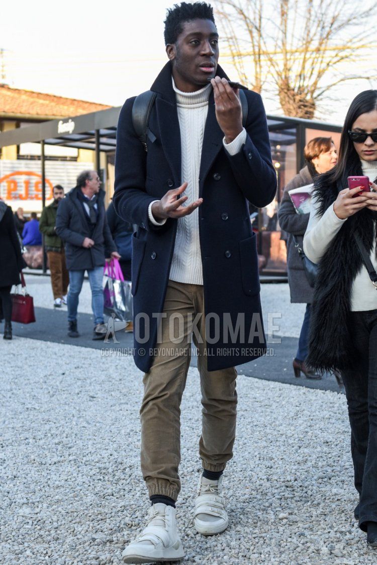 Men's fall/winter coordinate and outfit with dark gray solid color chester coat, white solid color turtleneck knit, beige solid color jogger pants/ribbed pants, dark gray solid color socks, and white high-cut sneakers.