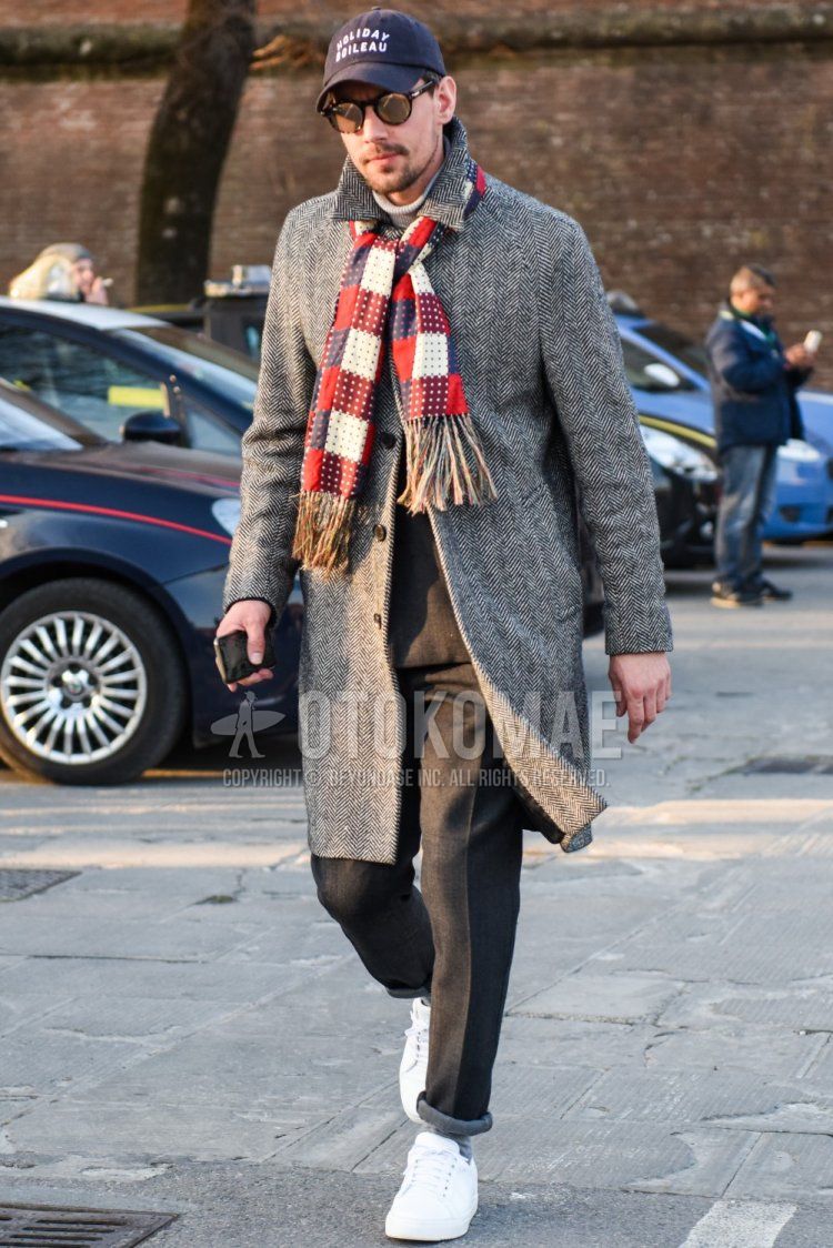 Men's fall/winter coordinate and outfit with black graphic baseball cap, solid black sunglasses, multi-colored scarf/stall, gray herringbone stainless steel coat, solid gray slacks, solid gray socks, and white low-cut sneakers.