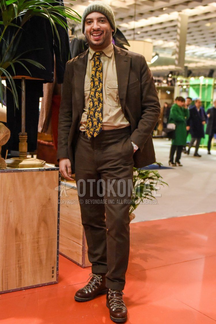 Spring and fall men's coordinate and outfit with olive green solid color knit cap, beige solid color shirt, brown boots, brown solid color suit, and multi-colored tie.