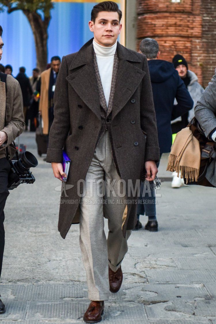 Men's fall/winter outfit with gray herringbone Ulster coat, gray checked tailored jacket, plain white turtleneck knit, plain gray slacks, plain gray socks, and brown tassel loafer leather shoes.