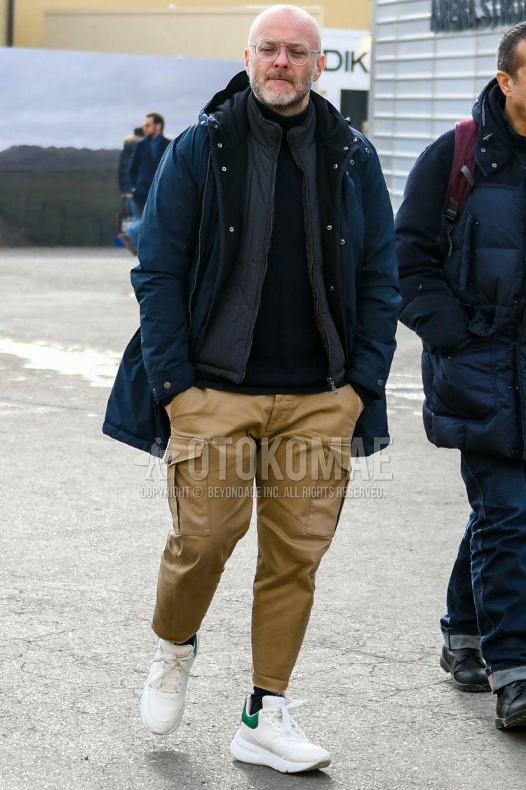 Winter men's coordinate and outfit with solid color glasses, solid color navy hooded coat, solid color black turtleneck knit, solid color dark gray inner down, solid color brown cargo pants, solid color navy socks, and white low-cut sneakers.