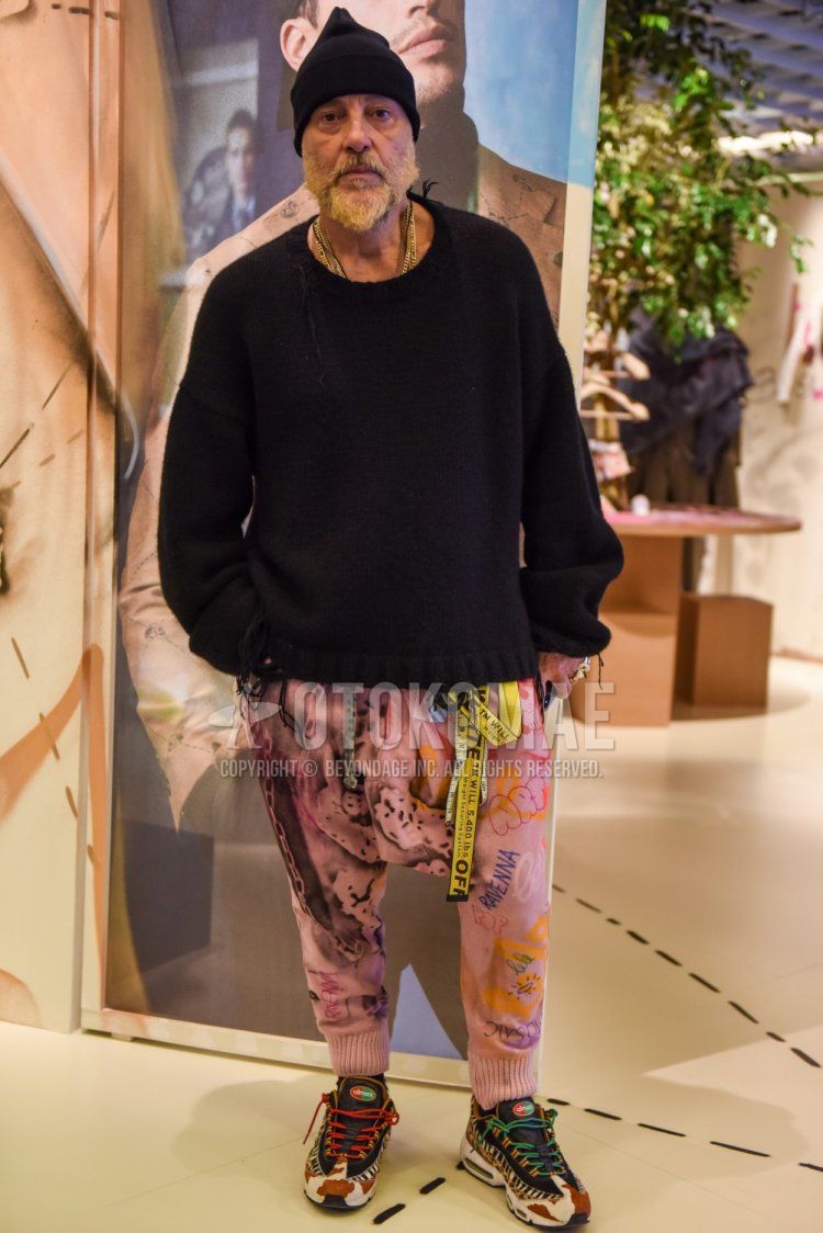 Men's spring and fall coordinate and outfit with plain black knit cap, plain black sweater, off-white yellow graphic tape belt, pink bottoms sarouel pants, and Nike Atmos Animal Pack Air Max 95 beige low-cut sneakers.