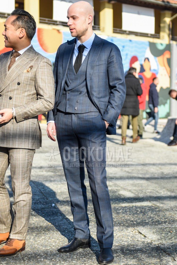 Men's spring and fall coordinate and outfit with plain light blue shirt, black side gore boots, gray checked three-piece suit, and plain black knit tie.