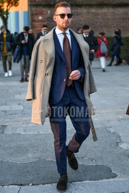 Men's fall/winter outfit with Ray-Ban Clubmaster thermomotor brown tortoiseshell sunglasses, beige check Ulster coat, plain white shirt, plain black socks, suede black plain toe leather shoes, dark gray plain suit, brown tie tie.
