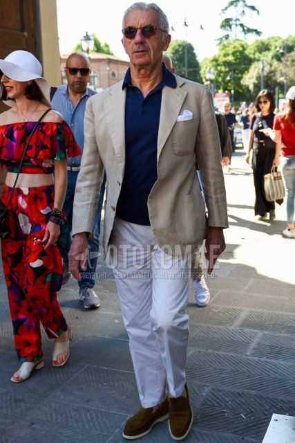 Men's spring and summer coordinate and outfit with brown tortoiseshell sunglasses, plain beige tailored jacket, plain navy polo shirt, plain white cotton pants, plain ankle pants, and brown slip-on sneakers.