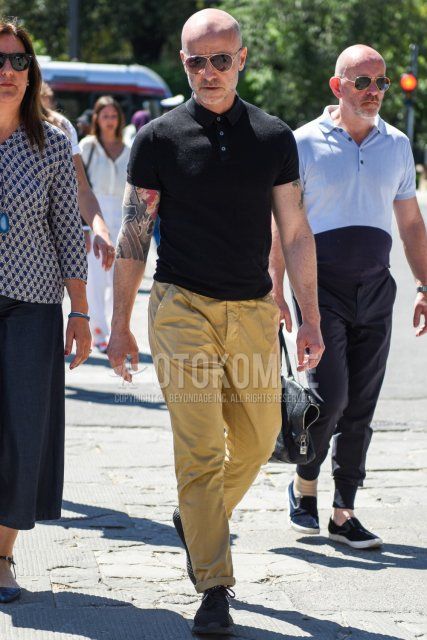 Summer men's coordinate and outfit with teardrop brown/silver solid sunglasses, solid black polo shirt, solid beige chinos, solid pleated pants, and black low-cut sneakers.