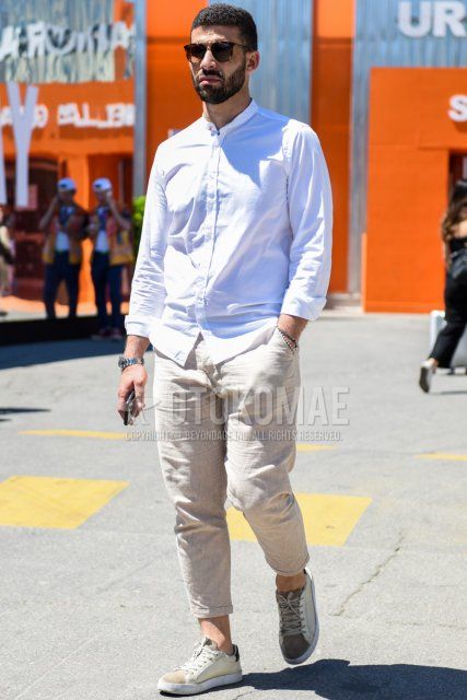 Men's spring/summer coordinate and outfit with black tortoiseshell sunglasses, plain white shirt, linen plain beige slacks, and white/beige low-cut sneakers.