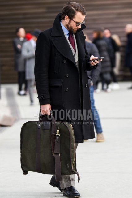 Men's fall/winter outfit with solid black sunglasses, solid black Ulster coat, solid light blue shirt, olive green border socks, black coin loafer leather shoes, solid olive green briefcase/handbag, solid gray suit, solid purple tie.