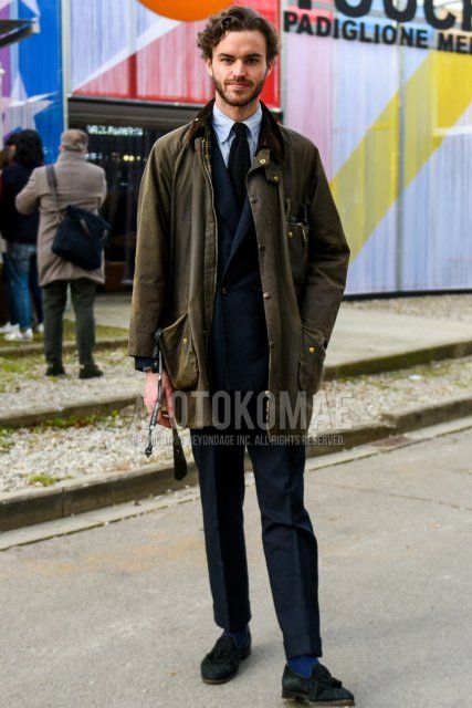 Winter men's coordinate and outfit with plain olive green field jacket/hunting jacket from Babur, plain light blue shirt, plain blue socks, suede black tassel loafer leather shoes, plain navy suit, and plain black knit tie.