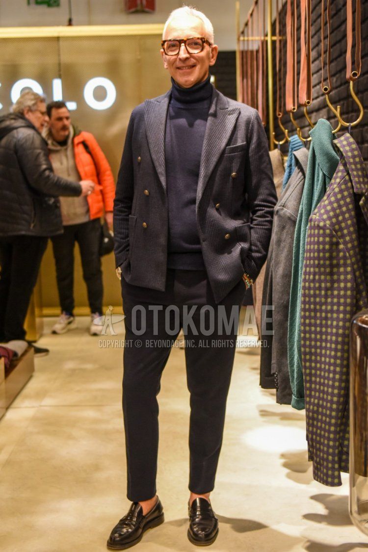 Men's spring and fall coordinate and outfit with brown tortoiseshell glasses, gray checked tailored jacket, dark gray solid color turtleneck knit, gray solid color slacks, gray solid color ankle pants, and black coin loafer leather shoes.