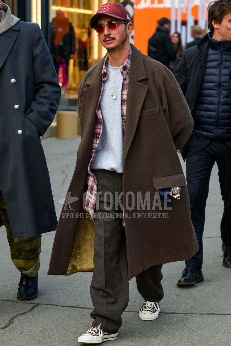 Men's fall/winter coordinate and outfit with New Era red lettered baseball cap, plain brown chester coat, multi-colored checked shirt, plain gray sweatshirt, plain gray slacks, and multi-colored low-cut sneakers.
