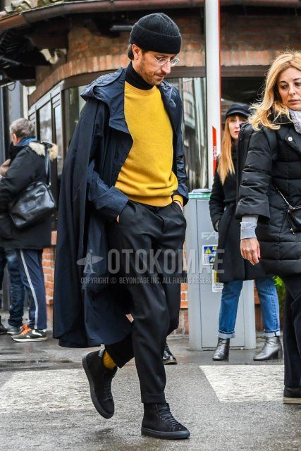 Winter men's coordinate and outfit with solid black knit cap, solid black hooded coat, solid yellow sweater, solid black turtleneck knit, solid dark gray slacks, and black high-cut sneakers.