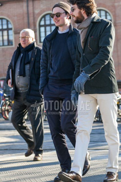 Men's fall/winter outfit with solid black knit cap, solid black sunglasses, solid dark gray down jacket, solid dark gray sweater, solid white shirt with band collar, solid gray slacks, and black brogue shoes leather shoes.