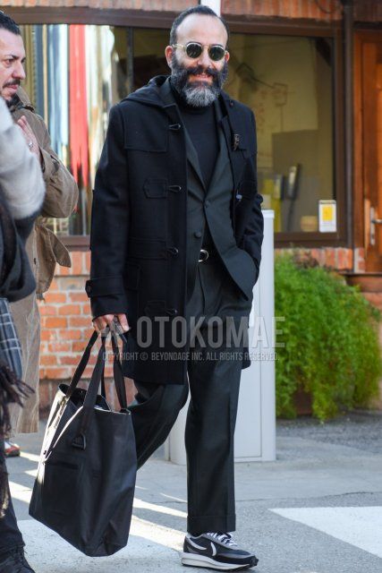 Men's fall/winter outfit and outfit with Boston clear solid sunglasses, solid black duffle coat, solid black turtleneck knit, Nike Sakai waffle gray/black low-cut sneakers, solid black tote bag, and solid gray suit.
