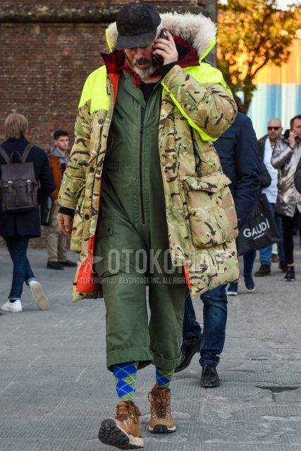 Winter men's coordinate and outfit with plain black baseball cap, beige/green camouflage down jacket, beige/green camouflage hooded coat, olive green plain jumpsuit, gray socks socks, brown boots.