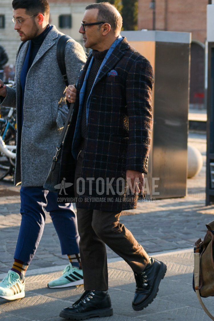 Men's fall/winter coordinate and outfit with plain black glasses, multi-colored checked chester coat, gray checked tailored jacket, plain gray turtleneck knit, plain brown slacks, black boots, and plain black shoulder bag.