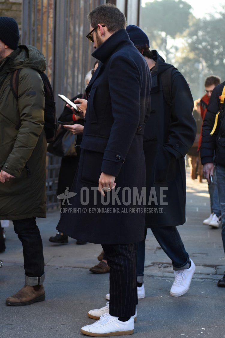Men's fall/winter coordinate and outfit with plain navy Ulster coat, dark gray striped slacks, plain black socks, and white low-cut Adidas sneakers.