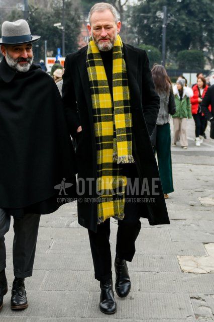 Men's fall/winter outfit with yellow/black checked scarf/stall, plain black chester coat, plain black turtleneck knit, plain black slacks, and black side gore boots.