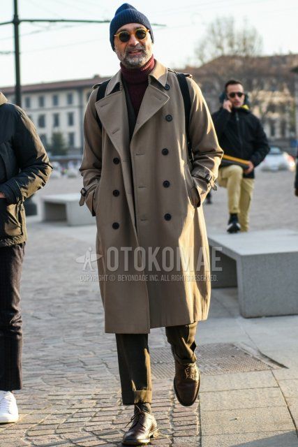 Men's fall/winter outfit with solid navy knit cap, solid beige sunglasses, solid beige trench coat, solid red turtleneck knit, solid gray socks, brown brogue shoes leather shoes, brown wingtip leather shoes, solid gray suit. .