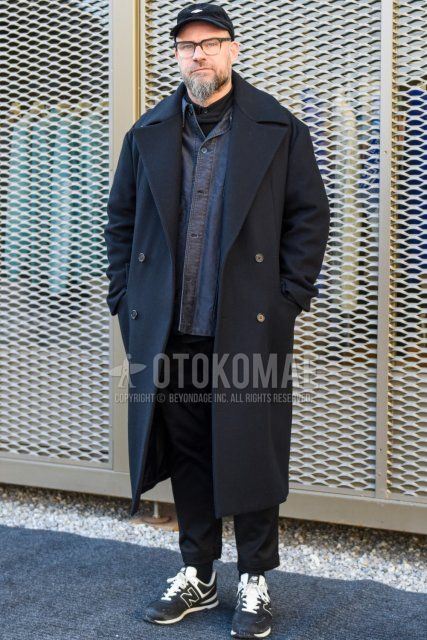 Men's fall/winter outfit with black one-point baseball cap, solid black glasses, dark gray solid Ulster coat, solid gray shirt, solid black shirt, solid black slacks, solid black cropped pants, solid black socks, black low-cut sneakers by New Balance Outfit.