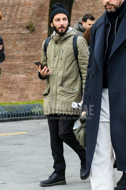 Men's spring and fall outfit with plain black knit cap, plain olive green mountain parka, plain gray slacks, and black wingtip leather shoes.