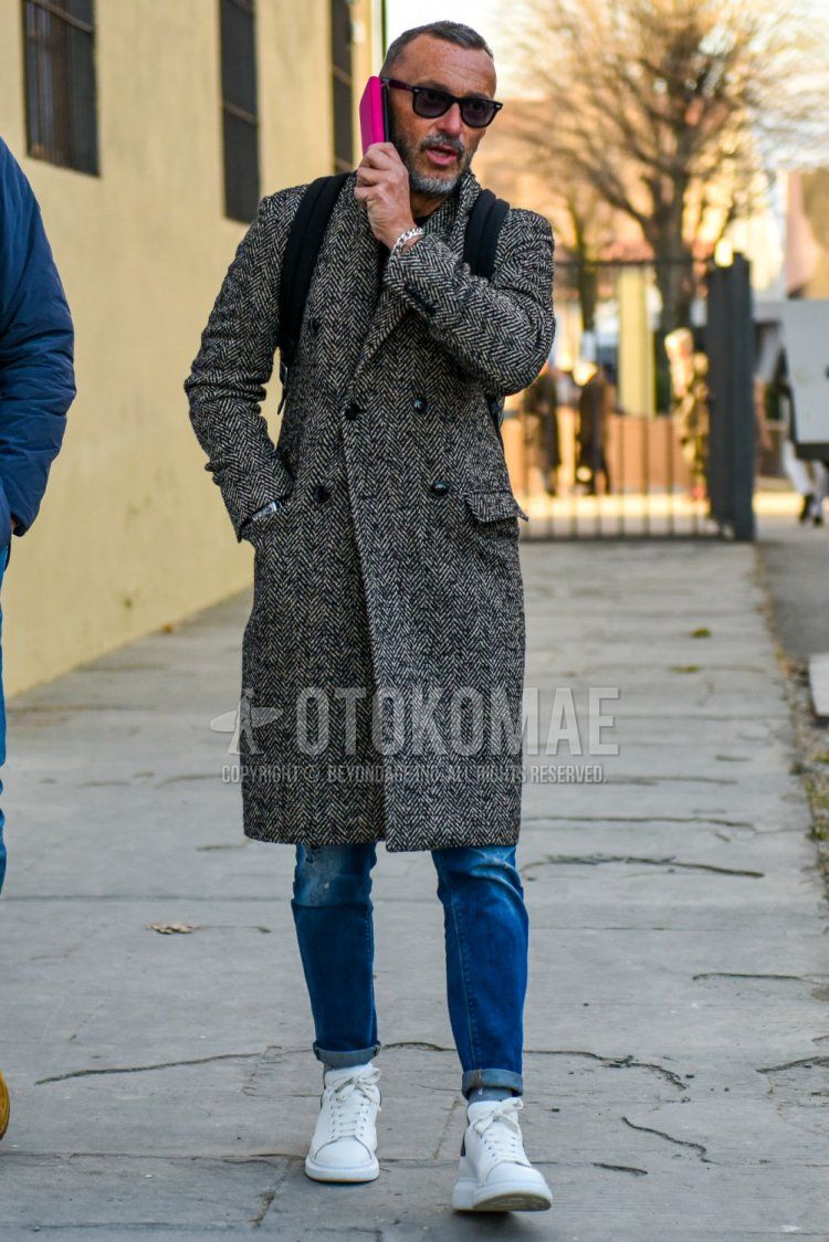 Men's fall/winter coordinate and outfit with Wellington plain black sunglasses, gray herringbone chester coat, plain blue denim/jeans, and Alexander McQueen white low-cut sneakers.