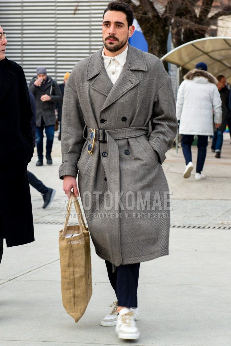 Men's fall/winter outfit with plain gray trench coat, plain white polo shirt, plain navy slacks, white low-cut sneakers, and solid beige briefcase/handbag.