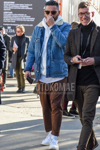Men's fall/winter outfit and outfit with Ray-Ban Clubmaster Thermont solid black sunglasses, solid blue denim jacket, white one-pointed hoodie, solid brown chinos, solid brown ankle pants, and white low-cut sneakers.