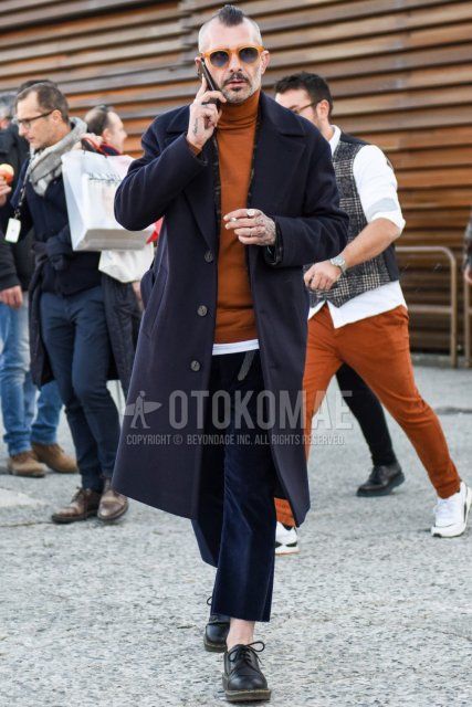 Men's fall/winter outfit with solid beige sunglasses, solid navy Ulster coat, solid brown turtleneck knit, solid white T-shirt, solid navy slacks, solid navy cropped pants, and black plain toe leather shoes.