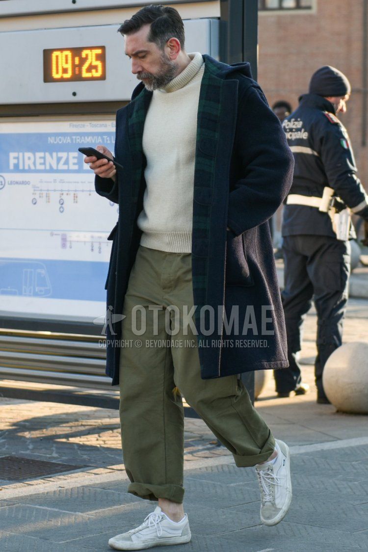 Men's fall/winter coordinate and outfit with plain black duffle coat, plain hooded coat, plain white turtleneck knit, plain olive green chinos, and Vans Old Skool white low-cut sneakers.