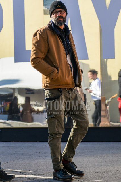 Black one-point knit cap, solid black glasses, Carhartt Detroit jacket solid beige shirt jacket, solid navy fleece jacket, solid black cardigan, solid brown leather belt, solid beige cargo pants, solid beige chinos, solid red socks, and black plain toe leather shoes.