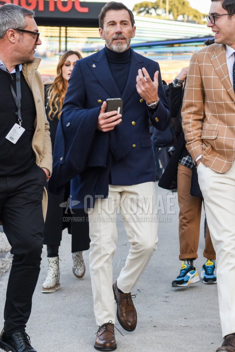 Spring and fall men's coordinate and outfit with plain navy tailored jacket, plain navy turtleneck knit, plain white slacks, plain white ankle pants, and brown wingtip leather shoes.