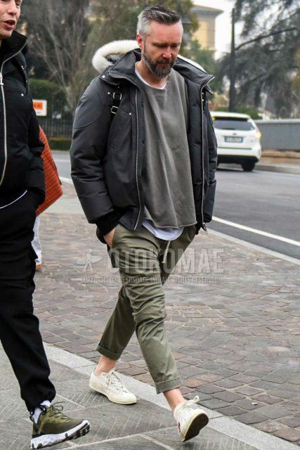 Men's fall/winter coordinate and outfit with plain gray down jacket, plain olive green/gray sweatshirt, plain white t-shirt, plain beige/olive green chinos, and Play Comme des Garcons Converse white low-cut sneakers.