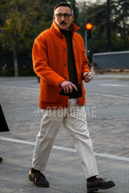 Men's fall/winter coordinate and outfit with brown tortoiseshell glasses, solid orange fleece jacket, solid black turtleneck knit, solid beige chinos, solid black socks, and brown leather shoes.