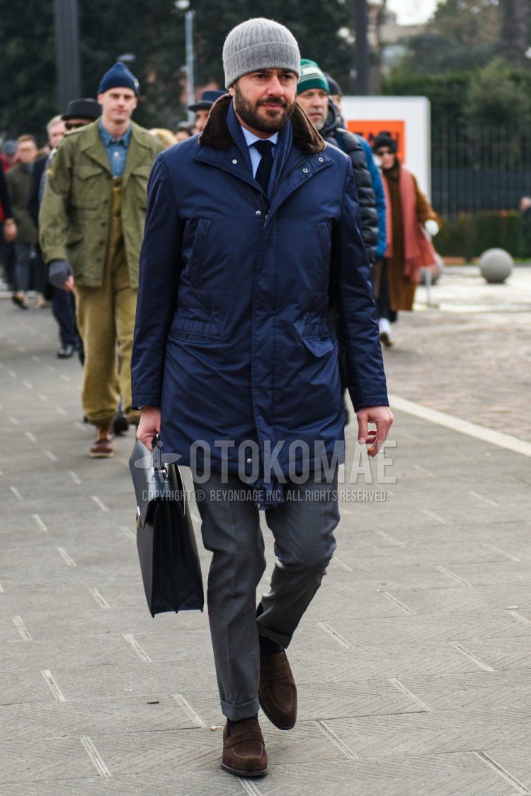 Men's fall/winter outfit with solid gray knit cap, solid gray scarf/stall, solid navy outerwear, solid light blue shirt, solid gray slacks, solid black socks, brown coin loafer leather shoes, suede shoe leather shoes, and solid black tie.