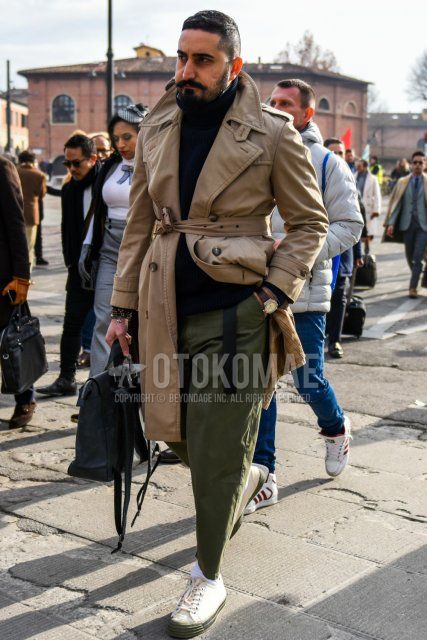 Men's fall/winter coordinate and outfit with plain beige trench coat, plain black turtleneck knit, plain olive green chinos, plain white socks, and white low-cut sneakers.
