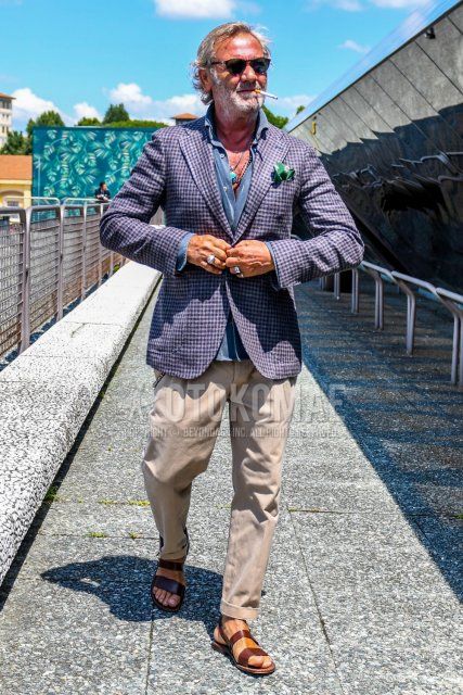 Men's spring/summer coordinate and outfit with solid color sunglasses, gray checked tailored jacket, solid color blue shirt, solid color beige pleated pants, solid color chinos, and brown leather sandals.