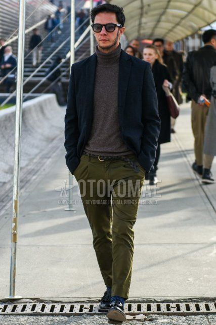 Men's fall/winter outfit with plain black sunglasses from Boston, plain navy tailored jacket, plain gray turtleneck knit, plain black leather belt, plain olive green chinos, blue striped socks, and black tassel loafer leather shoes.