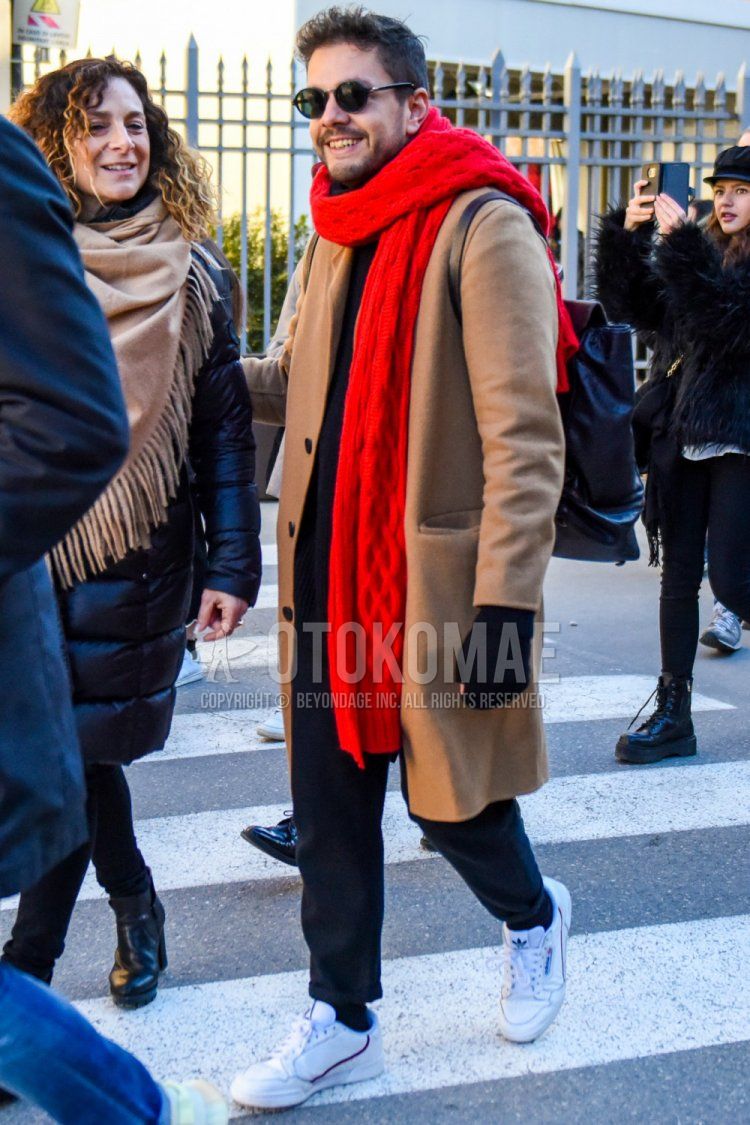 Winter men's coordinate and outfit with solid black sunglasses, solid red scarf/stall, solid beige chester coat, solid black cotton pants, and white low-cut Adidas sneakers.