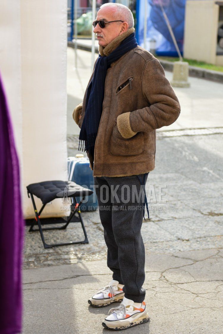 Men's fall/winter outfit with plain navy scarf/stall, plain brown leather jacket (not rider's), plain gray sweatpants, plain white socks, and white low-cut sneakers.